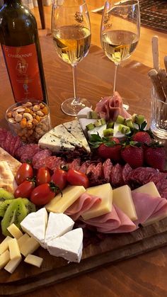 an assortment of cheeses, meats and fruit on a wooden platter