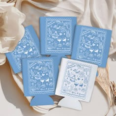 four blue cards with white designs are sitting on a table next to flowers and a flower pot