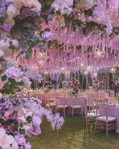 the tables are set with purple flowers and chandeliers hanging from the ceiling above them