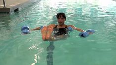 a woman in a swimming pool holding two blue dumbs