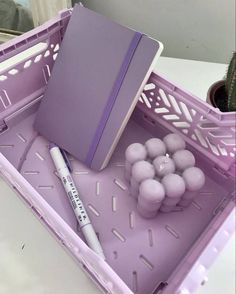 a purple container filled with balls and a pen