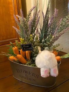 a white stuffed animal sitting inside of a metal container filled with flowers and plants