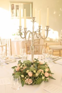 a centerpiece with flowers and candles on a table