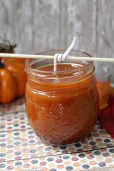 a glass jar filled with liquid sitting on top of a table next to pumpkins