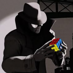 a man wearing a hat and holding a rube cube in his hands while looking at it