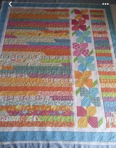 a quilted table runner with flowers and ribbons on the edges, in bright colors