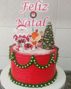 a red cake with white frosting and christmas decorations on top, sitting on a table