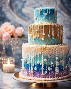 a multi layer cake with pearls and beads on it sitting on a table next to a candle