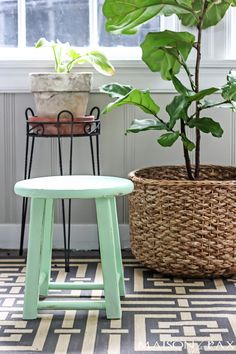 a green stool sitting next to a potted plant