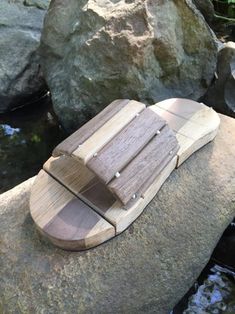 a small wooden boat sitting on top of a rock next to some water and rocks