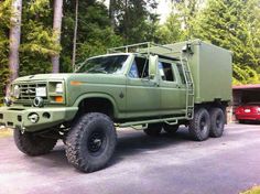 an army green truck parked in front of some trees