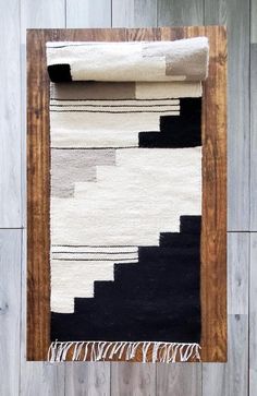 a black and white rug hanging on a wooden wall next to a wood frame with an area rug underneath it