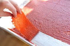 a person is spreading red paint on a piece of paper