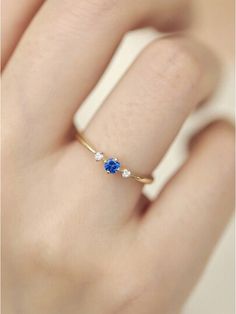 a woman's hand with a blue and white diamond ring on her left hand