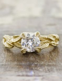 a yellow gold engagement ring with leaves on the band and a round diamond in the center