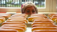 a woman looking at rows of glazed donuts