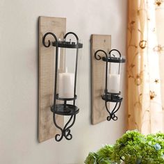 two wall sconces with candles on them are next to a vase filled with flowers