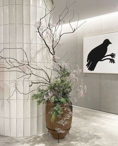 a vase with flowers in it next to a painting on the wall and a tree branch