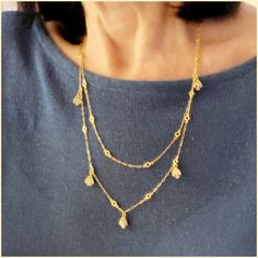 This beautiful necklace has a unique design - a very long chain that can be worn long or doubled, with the help of a toggle closure. It features tulip-shaped crystal drops set along half of the chain. Made of durable and beautiful 14kt gold-plated brass and enhanced with the finest European crystals. The full length is 42" or 20" when doubled. Made in the USA by La Vie Parisienne Gold Drop Chain Necklaces, Gold Drop Necklace With Chain, Gold Long Dangle Necklace With Chain, Gold Dangle Chain Necklace For Layering, Elegant Gold Lariat Necklace With Lobster Clasp, Elegant Brass Necklace With Double Chain, Elegant Brass Long Necklace With Adjustable Chain, Elegant Double Chain Brass Necklace, Delicate Gold Drop Lariat Necklace