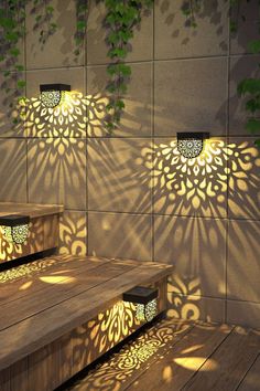 three wooden benches sitting next to each other in front of a wall with shadows on it