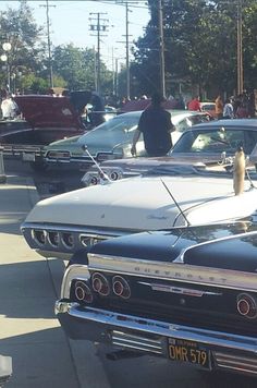 an old car parked on the side of the road with other cars in the background