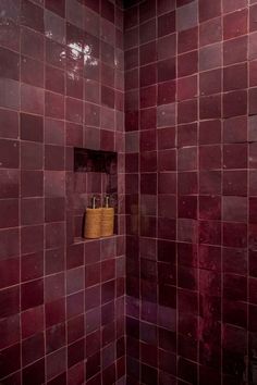 a bathroom with red tiles and a basket on the wall