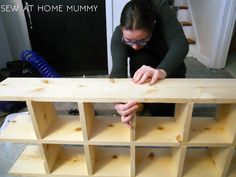 a woman working on a shelf made out of wood