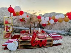 the table is set up with red, white and gold balloons in the shape of love