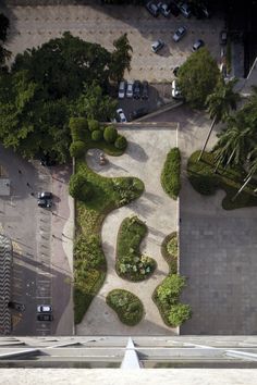 an aerial view of a parking lot with cars parked on the side and trees in the middle