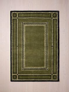 a green rug with an ornate border on the bottom and black trim around the edges