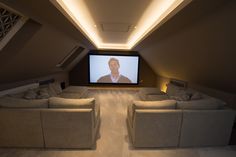 a room with two couches and a screen in the ceiling that has a man on it