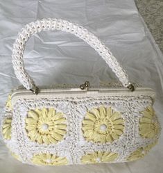 White/yellow bleached woven florals raffia with bead trim 1960's vintage top handle bag is so cute. The bag has an oval shape with a short top handle. The bag has a metal brass frame, with the raffia material wrapped around it. Thick brass kiss lock closure at the top center.  Raffia material is woven into floral patterns. Beads are adorning the flower patterns. The bag opens into a large cotton fabric lined compartment. There's a small pocket inside. The materials this bag is made of; raffia, b Yellow Vintage Bags, Spring Rectangular Straw Bag In Yellow, Yellow Rectangular Straw Bag For Spring, Spring Yellow Woven Bags, Vintage Handmade Handheld Straw Bag, Vintage Handheld Straw Bag Handmade, Vintage Yellow Bag For Spring, Vintage Yellow Bags For Spring, Handmade Vintage Handheld Straw Bag