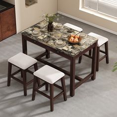 a dining table with four stools and plates on it in front of a window