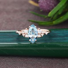 an oval cut blue topazte and diamond ring on a green piece of wood