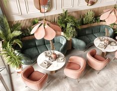 an overhead view of a restaurant with pink and green chairs, palm trees, and round tables