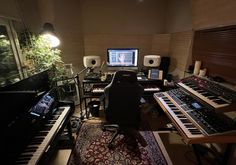 a recording studio with multiple keyboards, monitors and sound equipment in the room at night