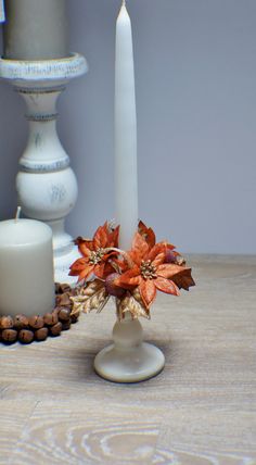 a white candle and some red flowers on a table with other items in the background