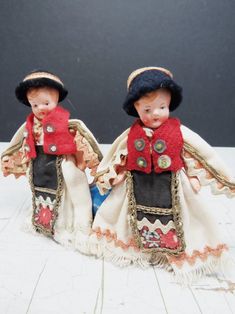 two small dolls are dressed in clothes and hats