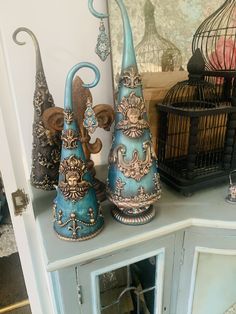 three blue vases sitting on top of a white cabinet next to a bird cage