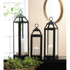 two black lanterns sitting on top of a table next to a basket filled with flowers