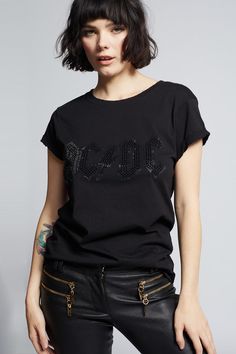 Step into the spotlight in this glittering AC/DC tee. The sleek design features the band's most iconic logo in stunning black crystals that will make you shine like a rock star. Our feminine fitted tee is made with soft cotton fabric, distressed hems, a ribbed crew neckline, and cuffed short sleeves. The design of this style is fitted. For a more standard fit, choose a size up. Details Style #200001 Color: Black Black Crystal AC/DC Logo Fitted T-Shirt Keyword: ACDC 100% Cotton Care/Import Machin Black Rhinestone T-shirt For Streetwear, Graphic Cotton T-shirt For Night Out, Edgy Cotton T-shirt For Night Out, Graphic Tee Cotton T-shirt For Night Out, Graphic Cotton Tee For Night Out, Rhinestone Embellished Short Sleeve T-shirt For Night Out, Black Cotton T-shirt With Rhinestones, Fitted Cotton Rock T-shirt, Rocker Style Top For Night Out