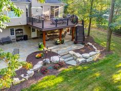 an aerial view of a home with landscaping and patio area in the foreground, surrounded by lush green trees