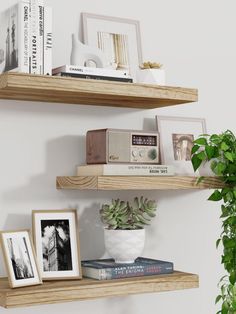 two wooden shelves with pictures, books and plants on them in front of a white wall