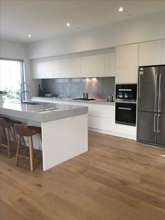 a modern kitchen with white cabinets and stainless steel appliances, along with hardwood flooring