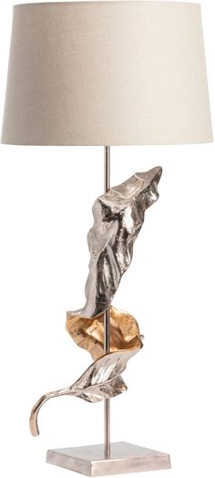 a table lamp with a silver and gold leaf design on the base, along with a white linen shade