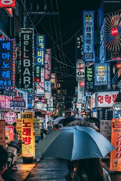 a woman holding an umbrella in the middle of a city at night with neon signs all around her