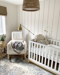 a baby's room with a crib, chair, and rug in it