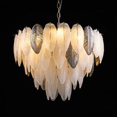 a white chandelier with feathers hanging from it's center and four lights on each side