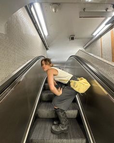 a woman riding down an escalator with her hand on her purse and boots