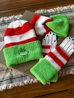 two knitted hats and mittens sitting on top of a table